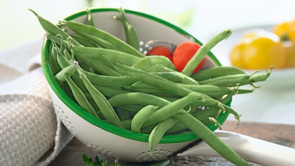 Frische Stangenbohnen und zwei Tomaten in einer Schale