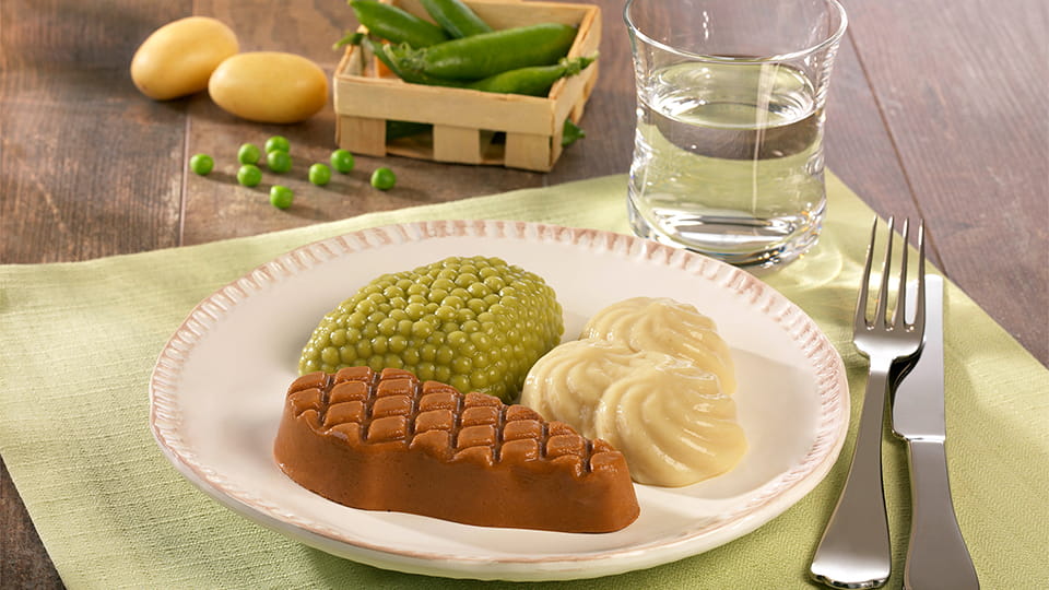 Püriertes Menü auf einem Teller mit geformtem Gemüse, Kartoffeln und Fleisch