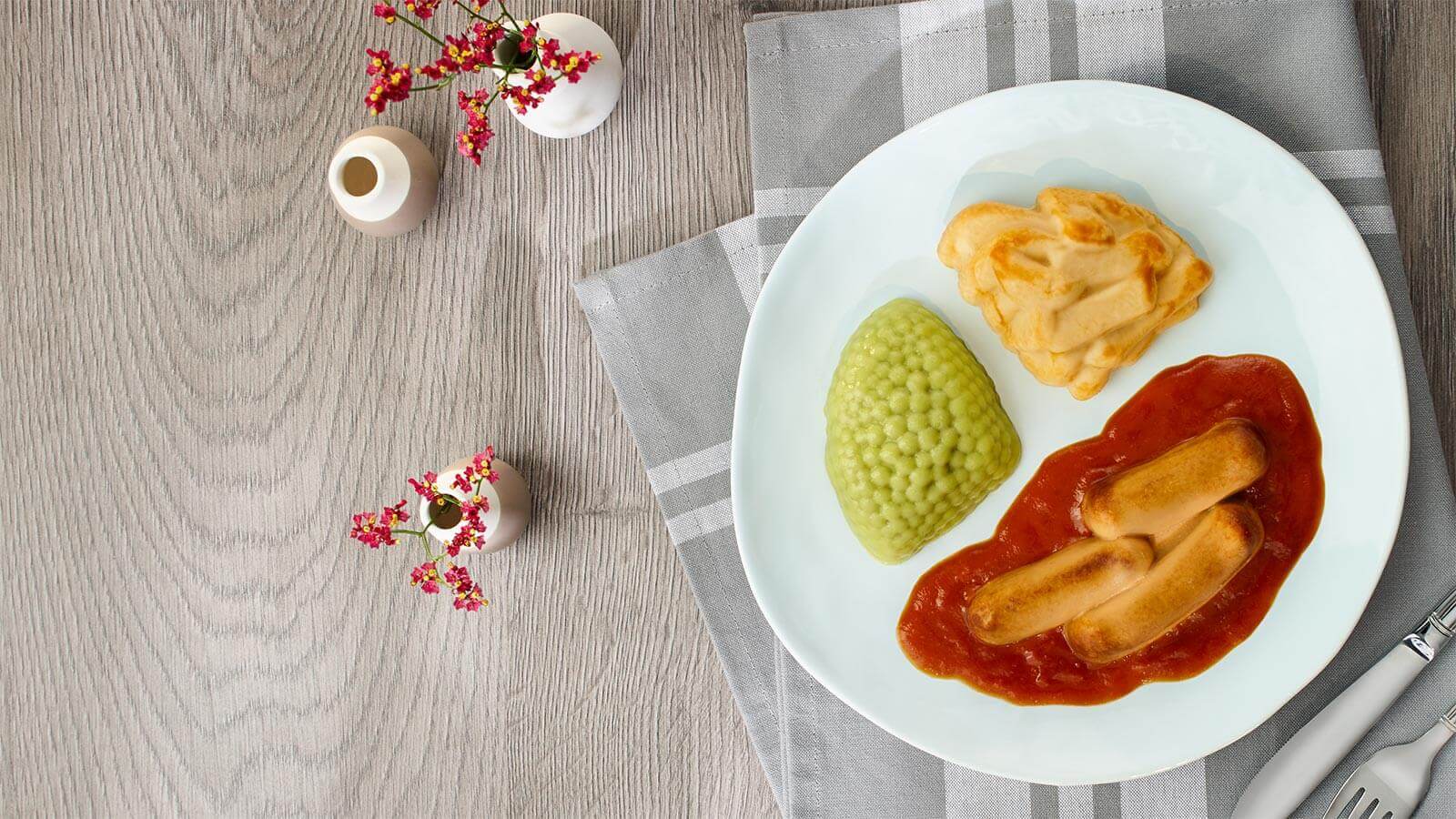 Püriertes Menü geformt zu Currywurst mit Kartoffeln und Erbsen