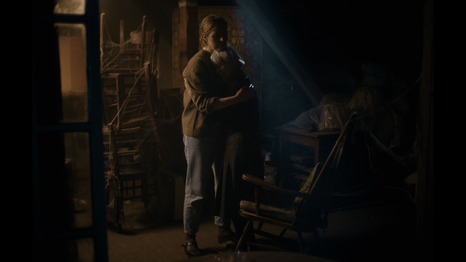 Mutter und erwachsene Tochter umarmen sich in einem dunklen Raum