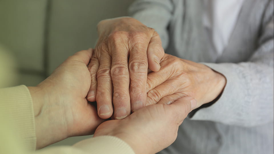 Ältere und jüngere Person halten Hände