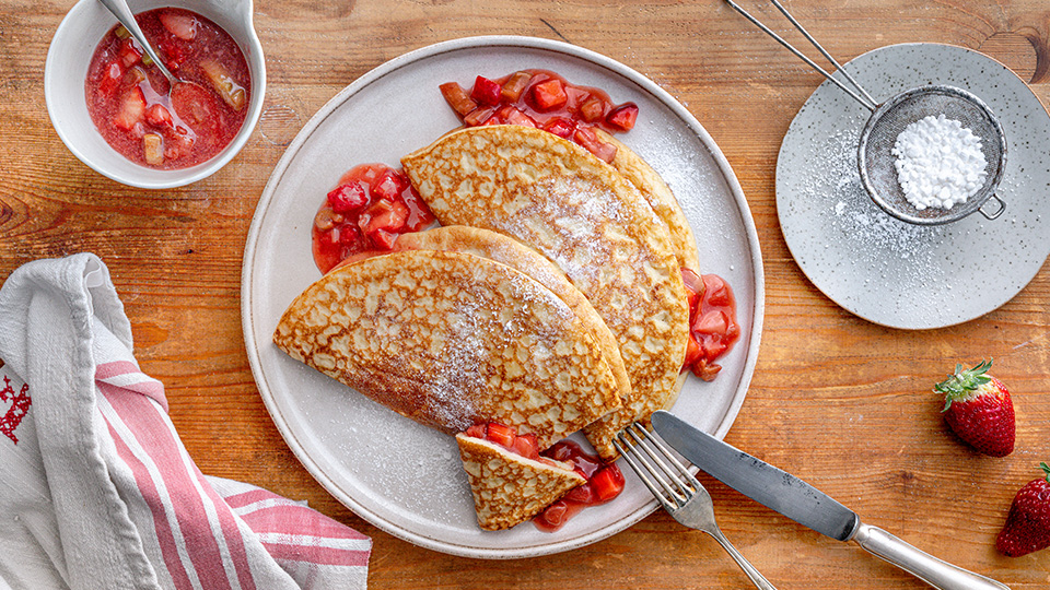 goldbraune Pfannkuchen mit Erdbeer-Rhabarberfüllung und Puderzucker bestreut