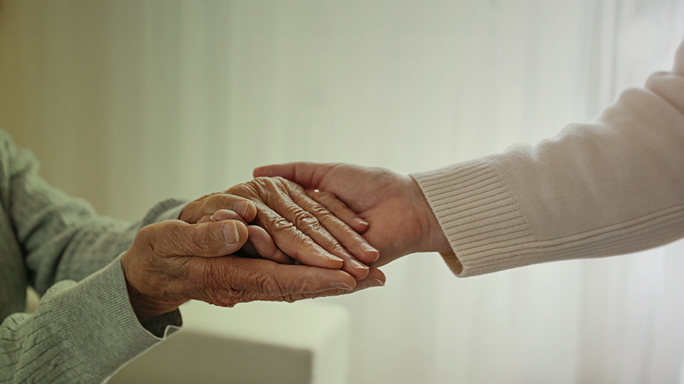 Zwei ältere Hände halten eine jüngere Hand