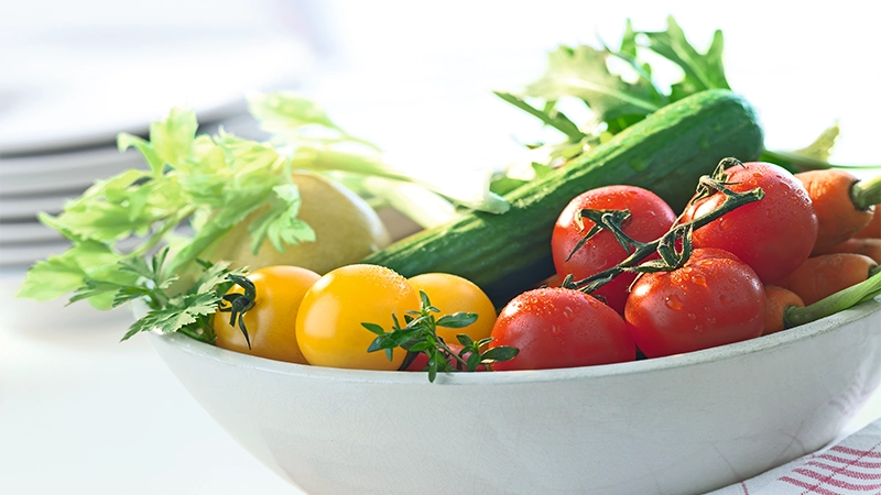 Eine schale mit raten und gelben Tomaten und einer Gurke
