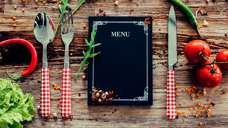 Menükarte mit Besteck auf Holzhintergrund