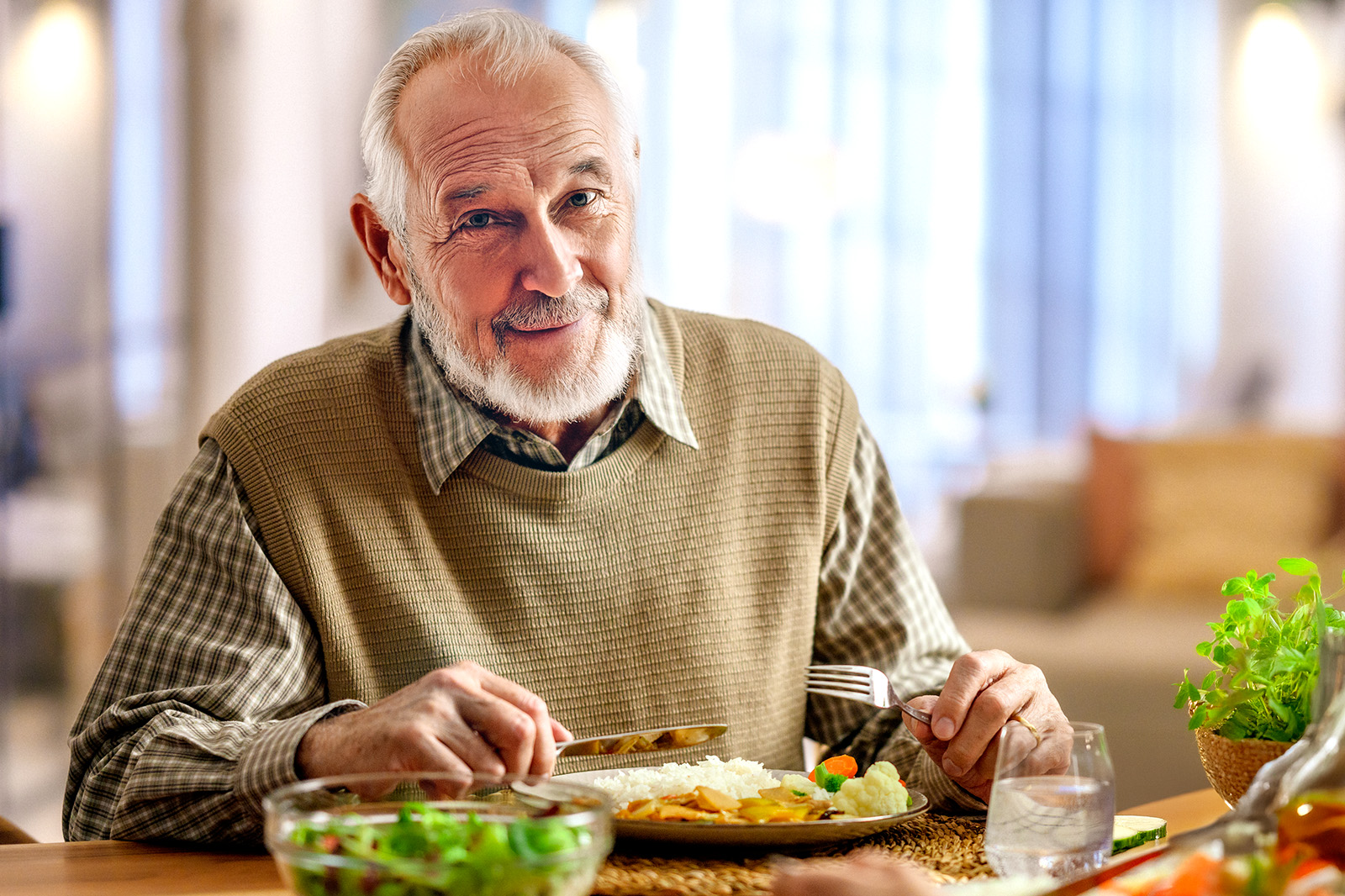Älterer lachender Mann beim Essen am Tisch