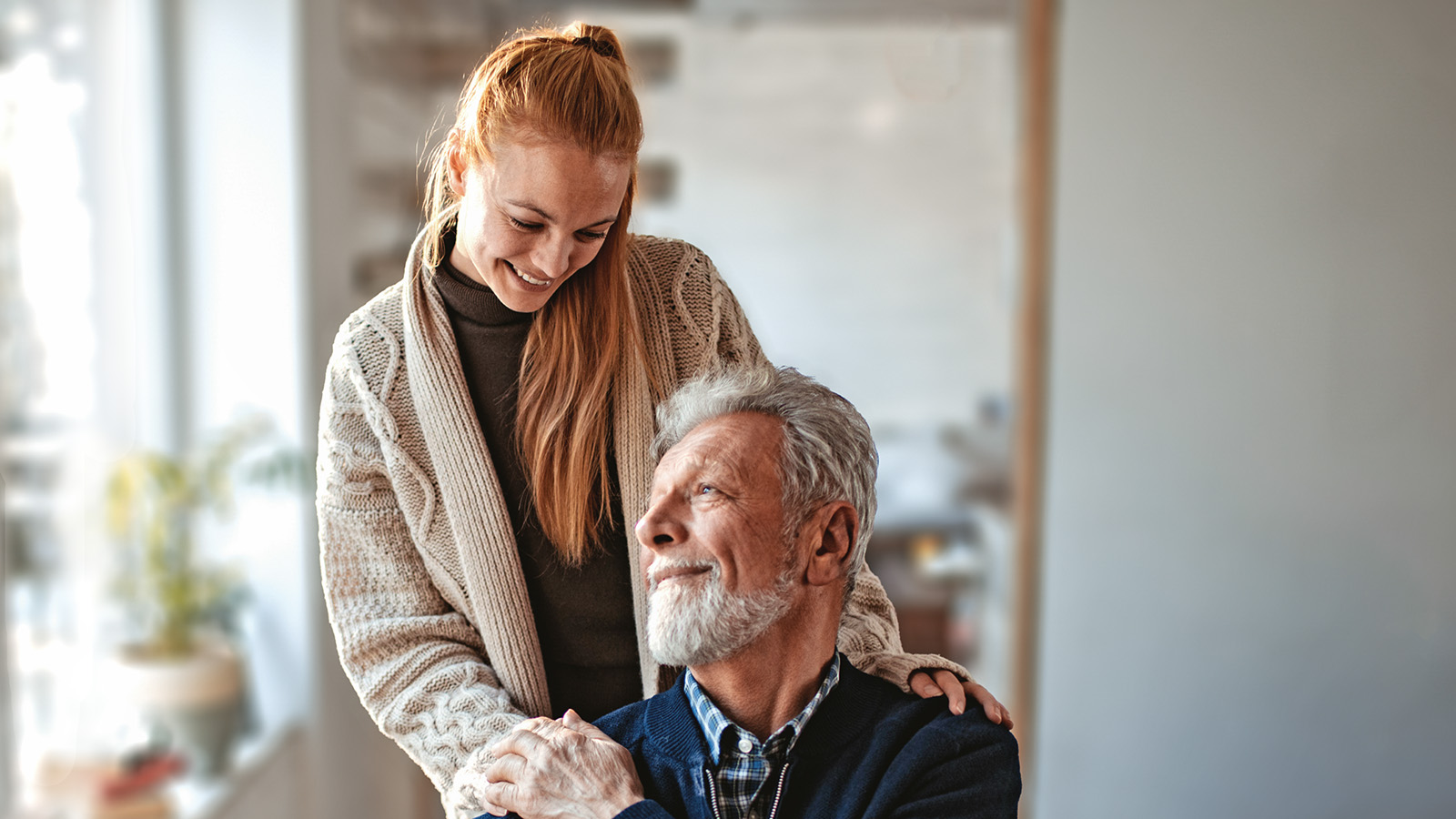 junge Frau lacht einem sitzendem älteren Mann zu