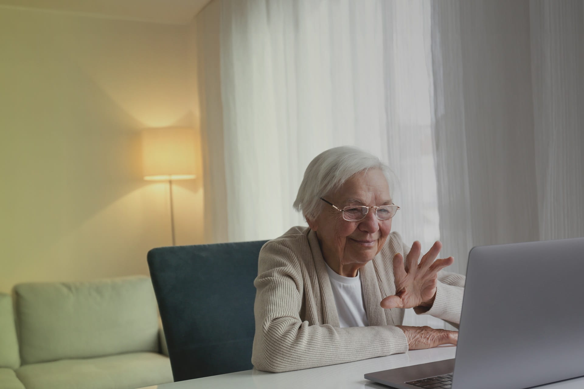 Ältere Damen schaut in einen Laptop und winkt