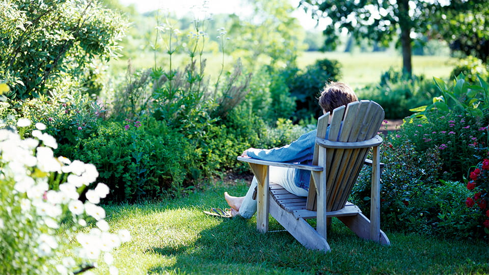 Frau sitzt auf einem Gartenstuhl im Grünen