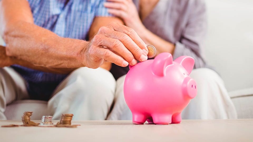 Älteres Paar wirft Münze in ein Sparschwein