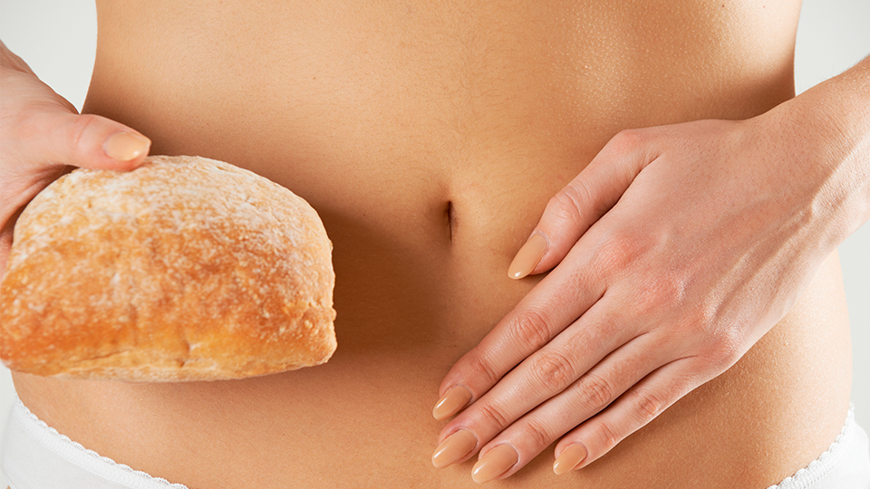 Frau hält sich den Bauch und in der anderen Hand ein Stück Brot