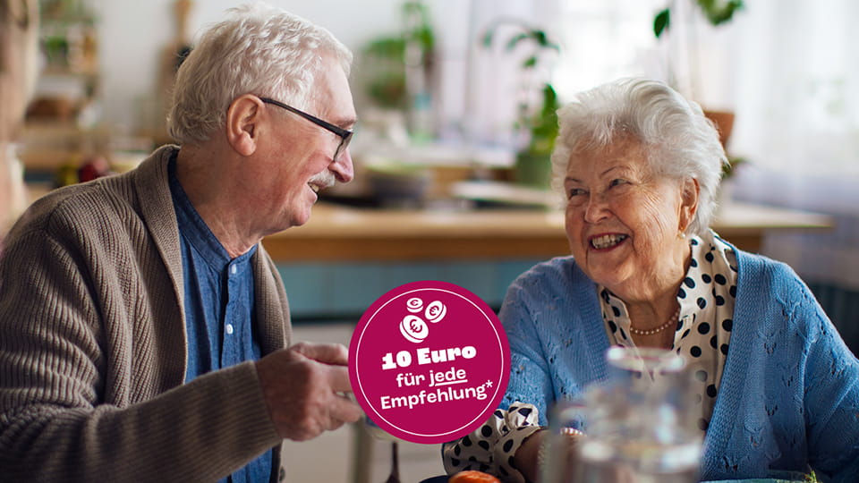 Lachendes älteres Paar sitzt zusammen am Tisch, darunter ein Kreis mit dem Hinweis:10 Euro für jede Empfehlung