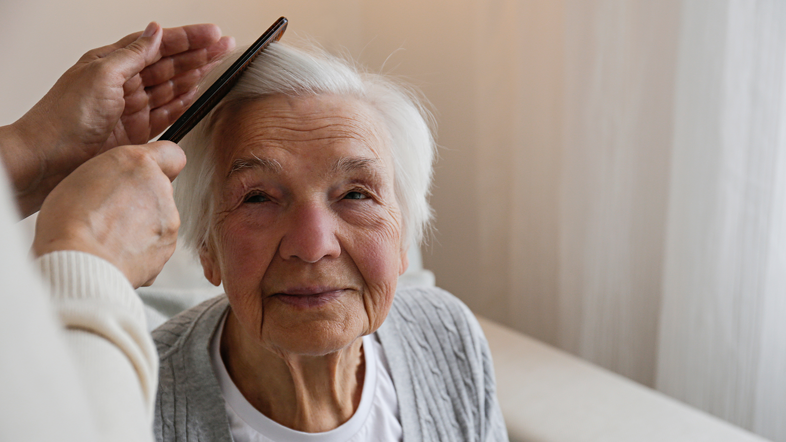 Älterer Frau werden die Haare gekämmt