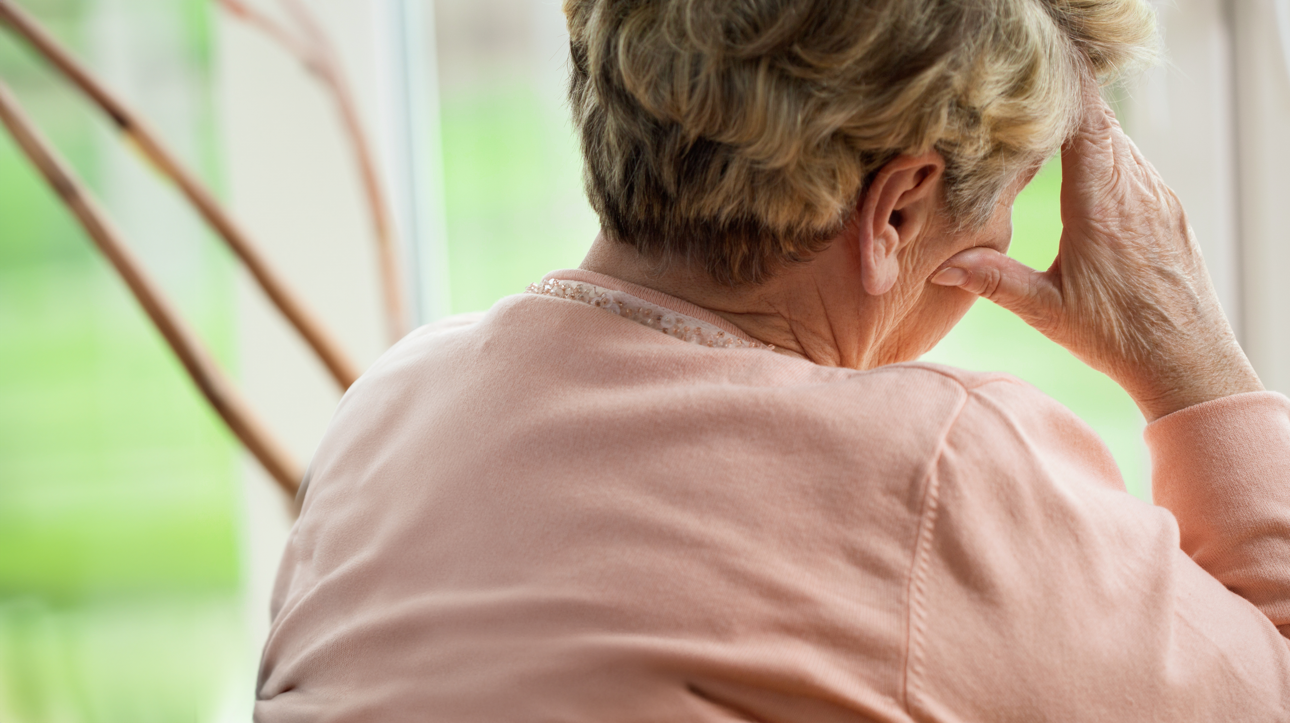 Seniorin von hinten, die den Kopf auf der Hand abstützt