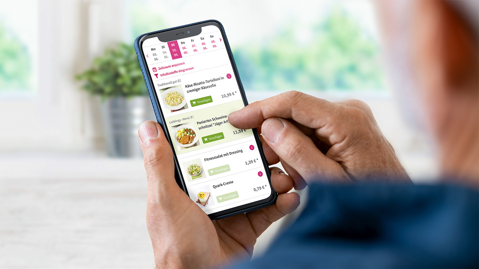Senior hält Smartphone in den Händen und bestellt in der App der Landhausküche.