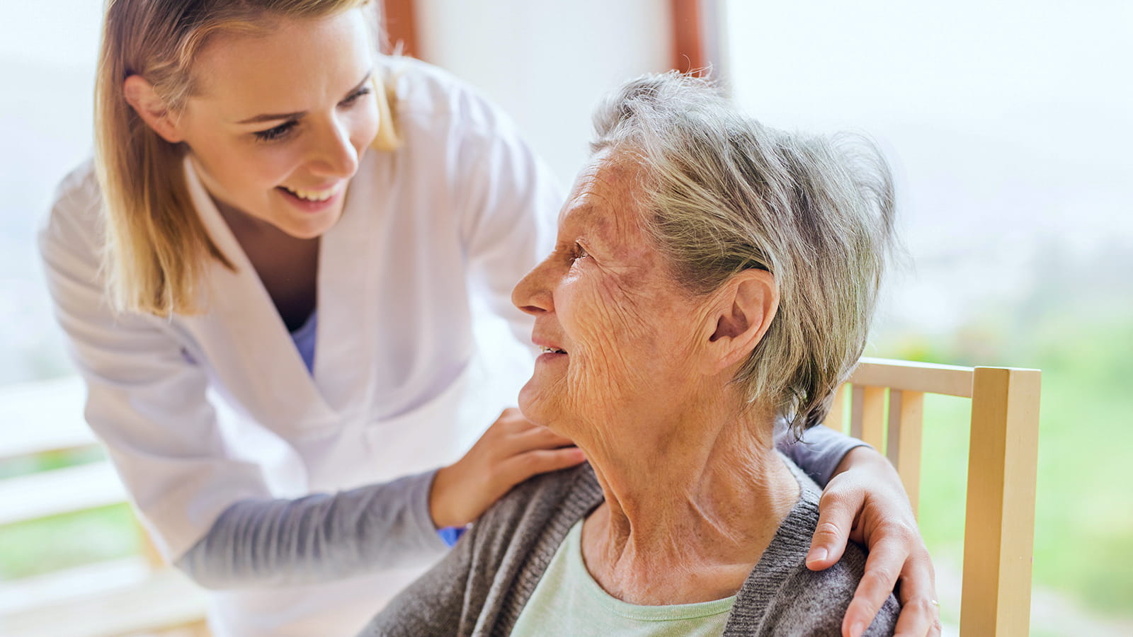 Eine Pflegerin hilft einer älteren Dame während eines Hausbesuchs.