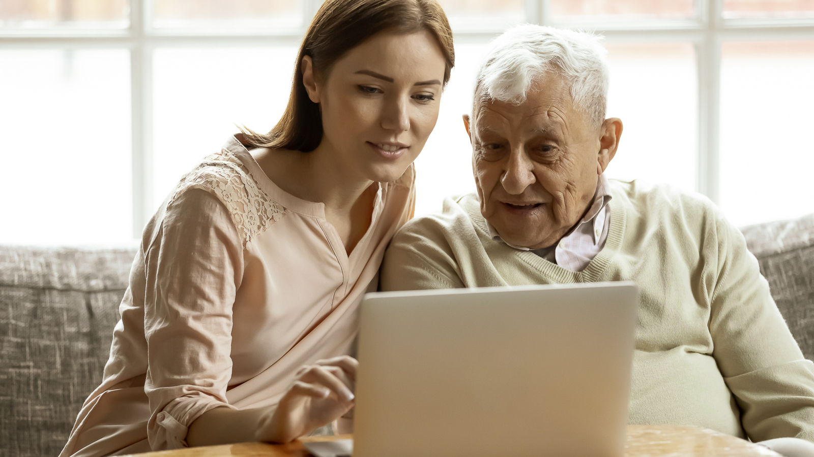 Tochter hilft ihren Vater am Laptop.