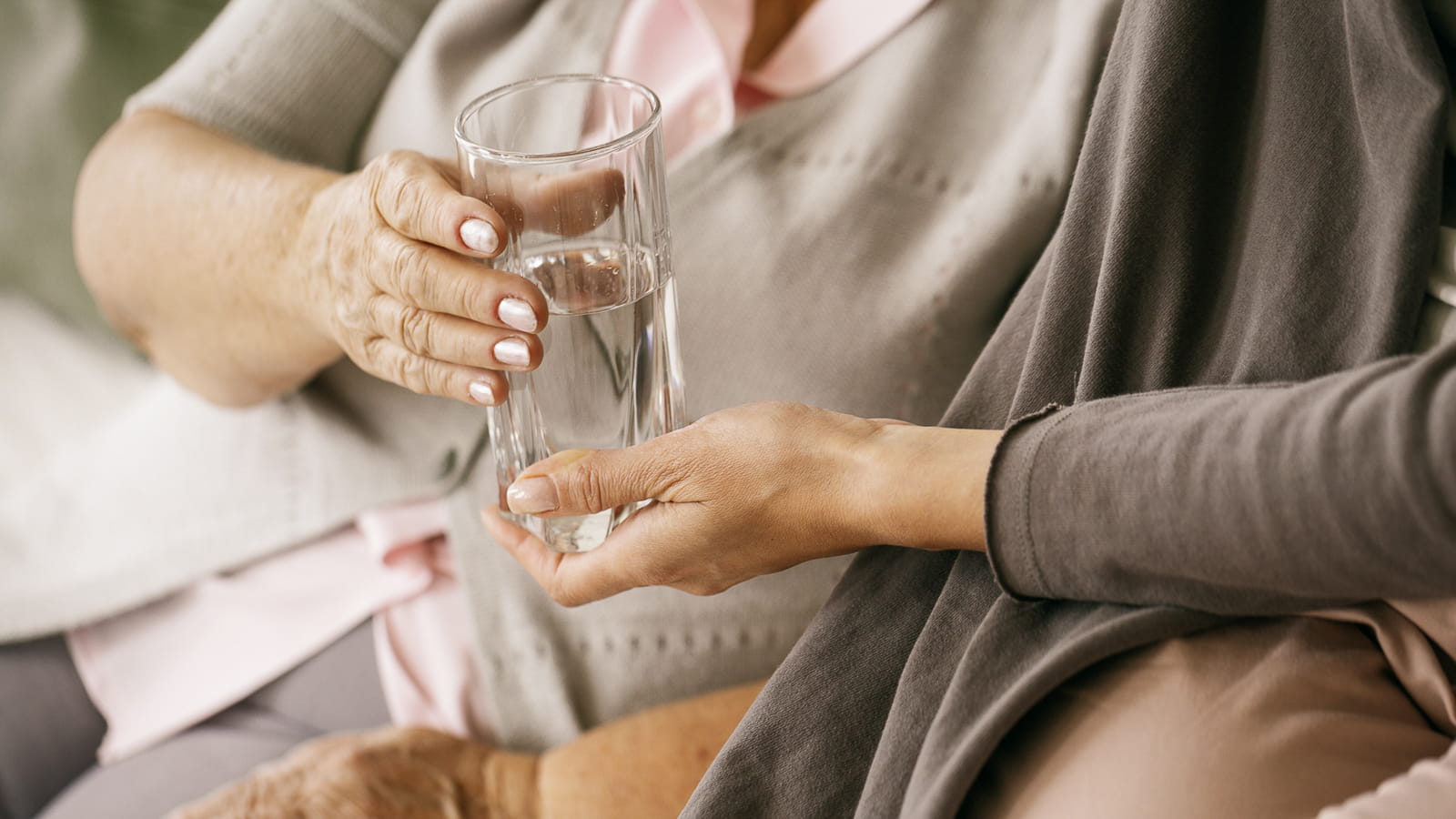 Ältere Dame nimmt ein Glas Wasser entgegen. 