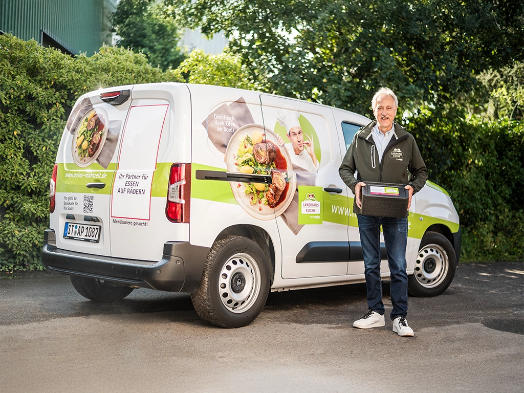 Ein Menükurier steht vor seinem Frischemobil