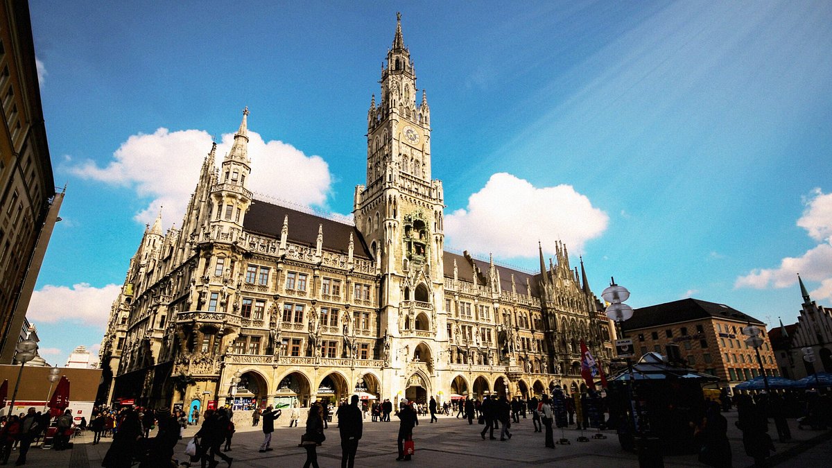 Historisches Rathaus mit großem Turm am Marienplatz in München, davor Menschen und blauer Himmel