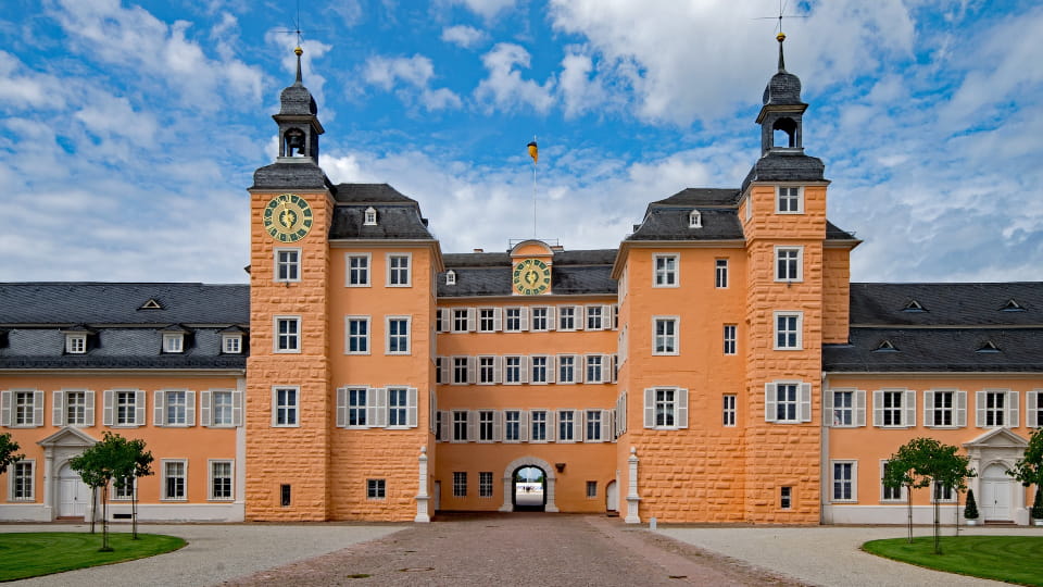 großes Schloss mit zwei Türmen, hellorange Fassade und Innenhof