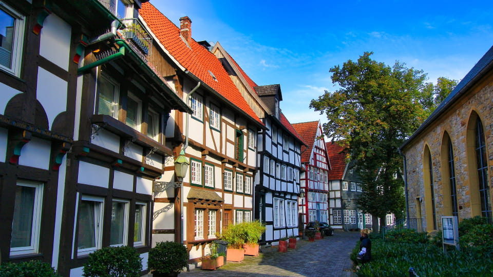 Schmale Gasse mit malerischen Fachwerkhäusern und Pflastersteinen in Gütersloh bei sonnigem Wetter