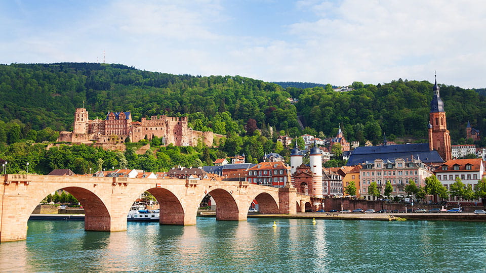 Alte Brücke und Schloss vor grüner Bergkulisse in Heidelberg