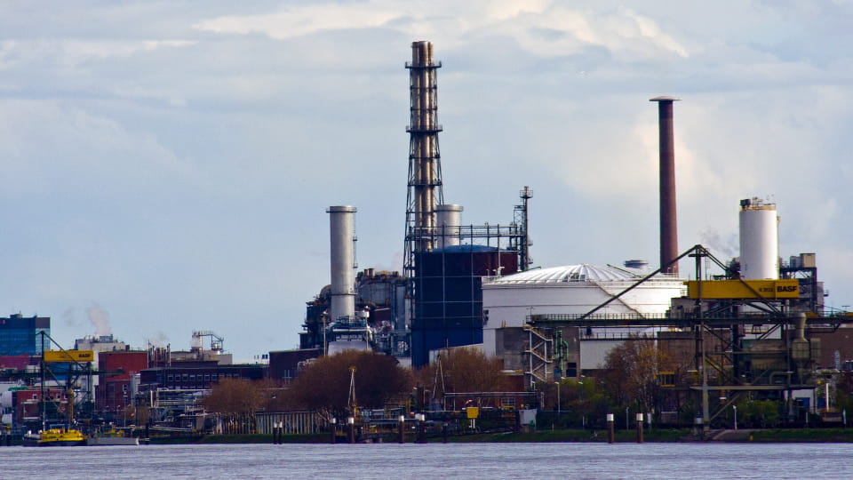 Industrieanlage in Ludwigshafen mit Schornsteinen, Kränen und Fabrikgebäuden am Flussufer