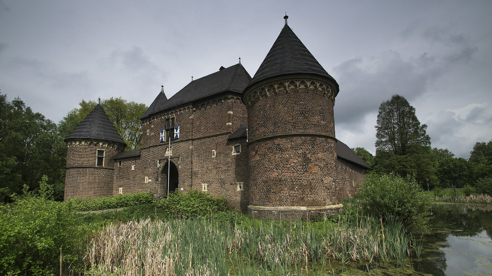 Alte Burg in Oberhausen mit Türmen und Spitzdächern, umgeben von Wassergraben in der Natur