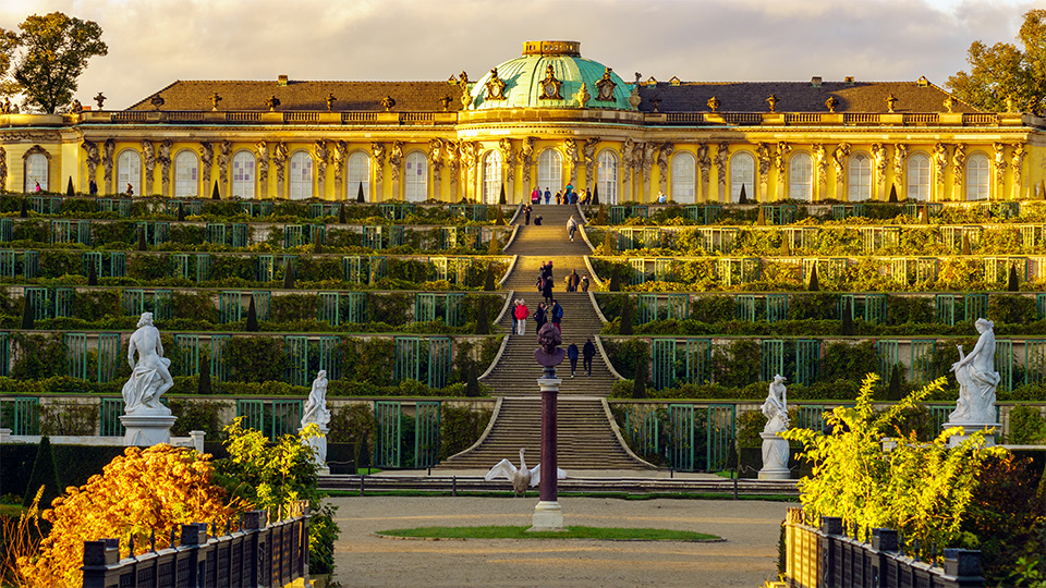 Schloss Sanssouci mit seinen terrassenförmig angelegten Weinbergen, Treppenaufgang und Statuen in Potsdam bei Sonnenuntergang