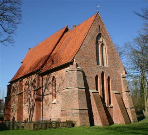 Klosterkirche mit rotem Backstein und spitzem Dach vor blauem Himmel