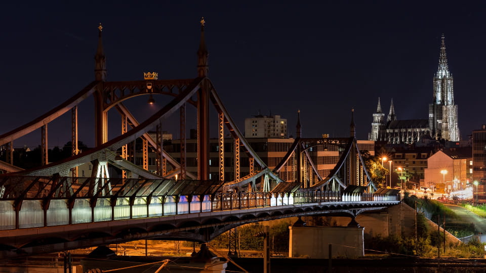 Beleuchtete Neutorbrücke und Kirchturm in Ulm bei Nacht